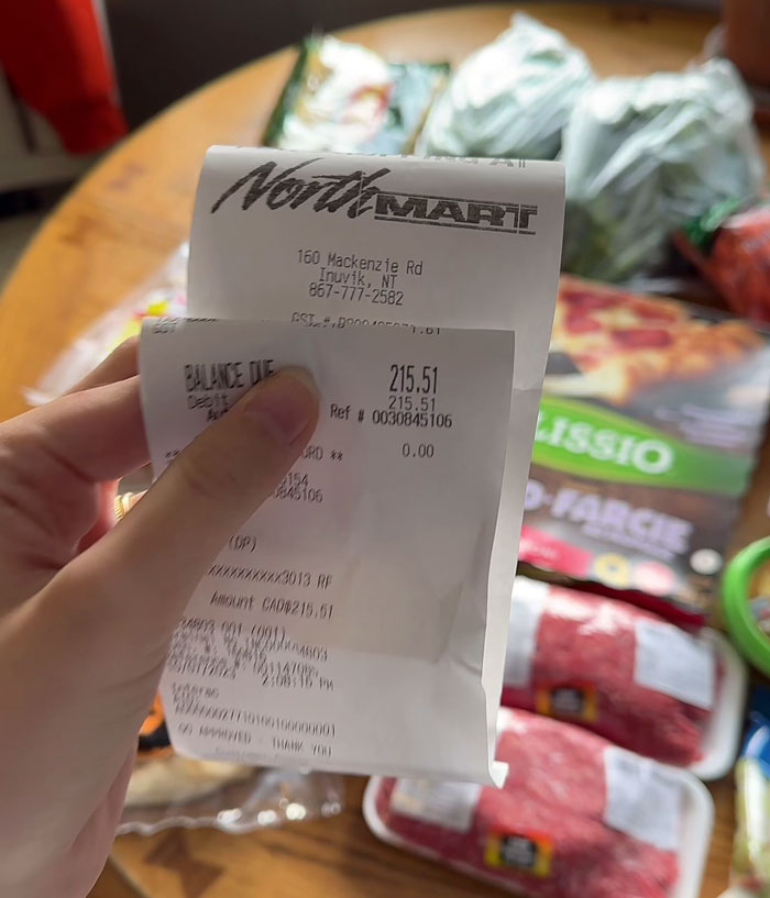 Receipt showing expensive grocery cost in the Arctic, totaling CAD 215.51, with groceries in the background.