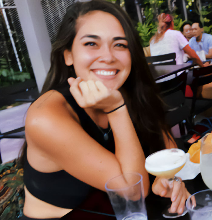 Woman smiling at a table with a drink, focusing on her healing journey.