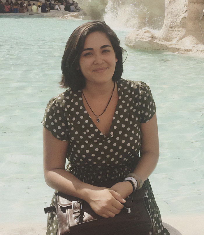 Woman in polka dot dress sitting near a fountain, linked to green card marriage scam case.