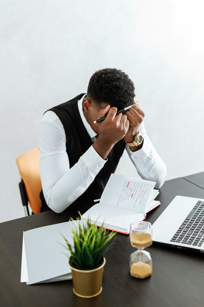 Man stressed at desk with notebook and laptop, related to relationship red flag professions.