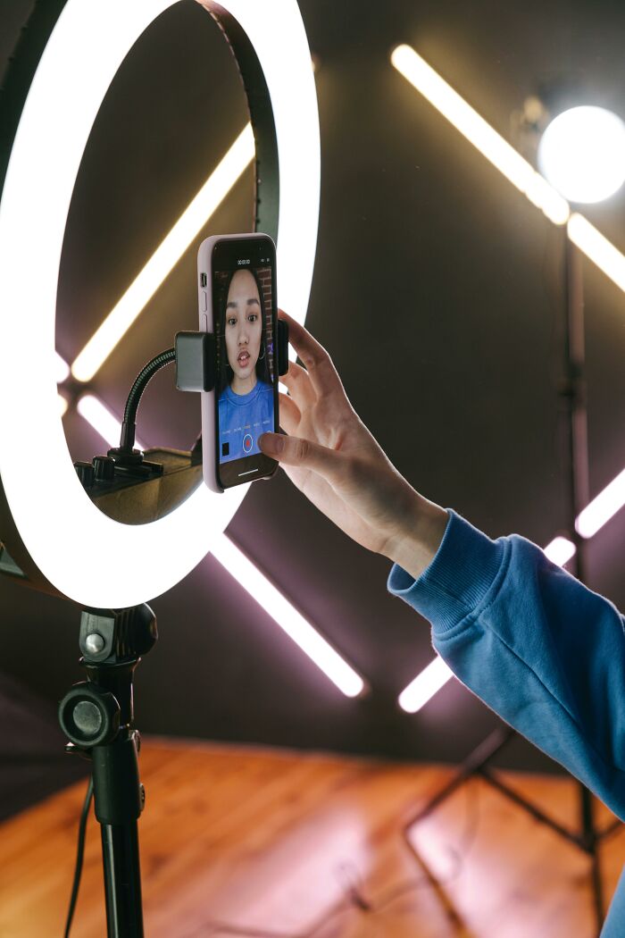 Person in blue recording video on phone with a ring light, illustrating professions seen as relationship red flags.