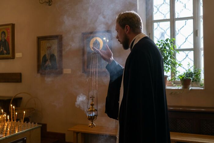 Person in religious attire with incense, often seen as a relationship red flag profession, inside a church setting.