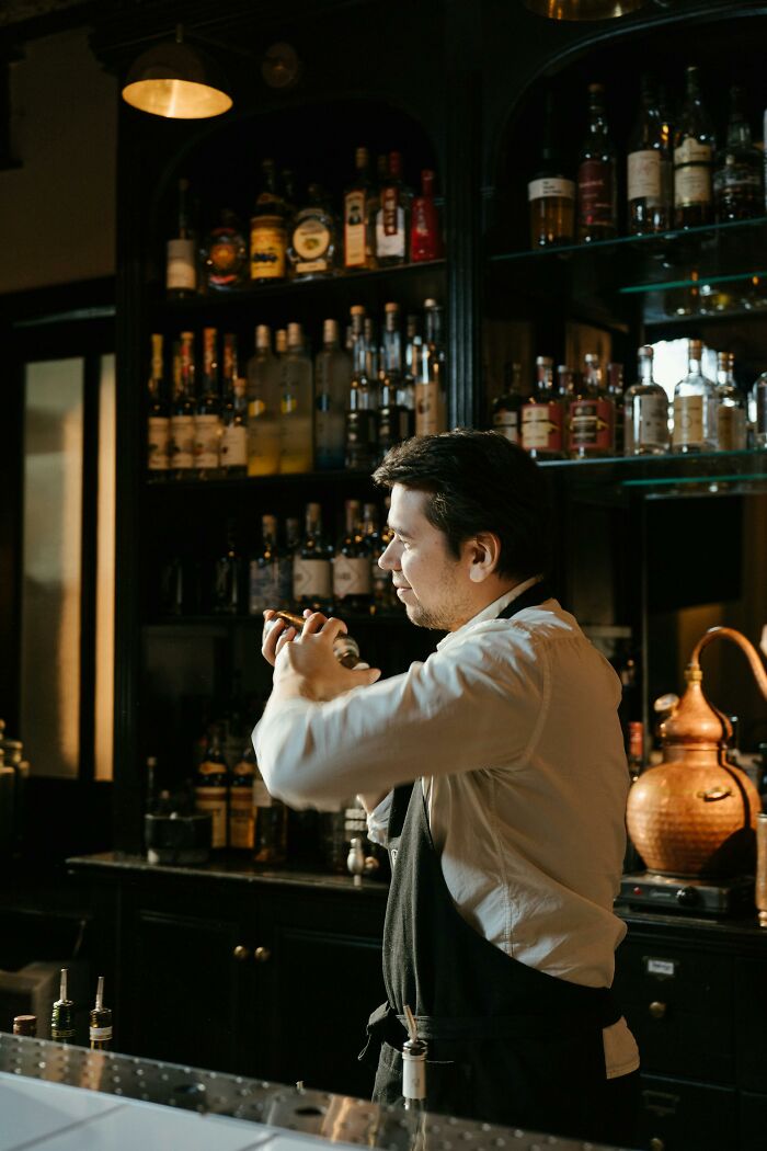 Bartender mixing a drink in a dimly lit bar, highlighting a profession some view as a relationship red flag.