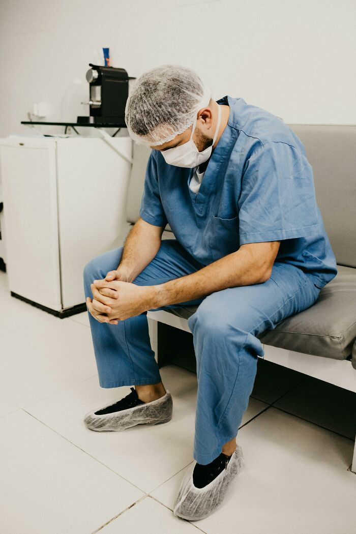 Healthcare professional in scrubs sitting pensively, suggesting relationship red flags.