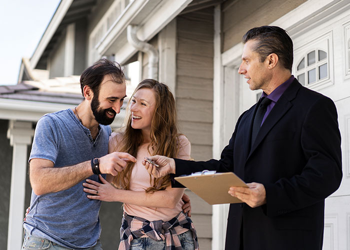 Homeowners confront HOA representative over fake violations, standing outside their house with a clipboard.