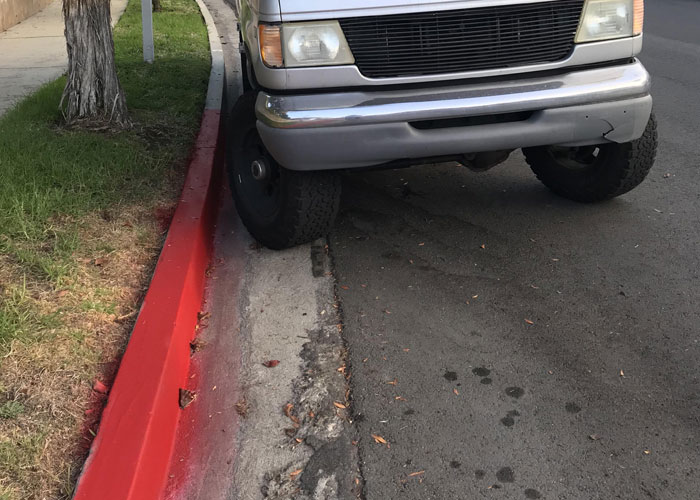 Truck parked with tire on red curb, symbolizing HOA fake violations dispute.