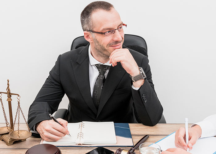 Man in a suit at a desk, taking notes, with scales of justice; concept of HOA fake violations.