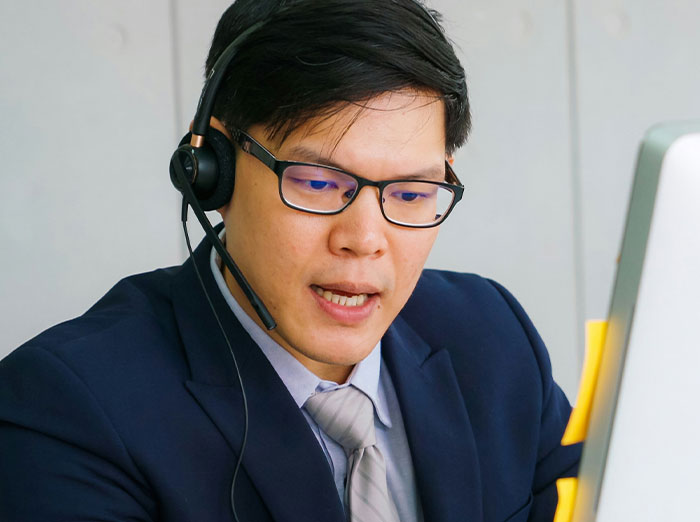 Bank representative assisting a customer call, wearing glasses and a headset, focused on solving a card issue.