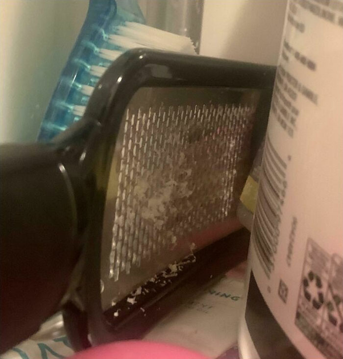 Grater with leftover food next to a toothbrush and cleaning products, illustrating horrible roommates' messy habits.