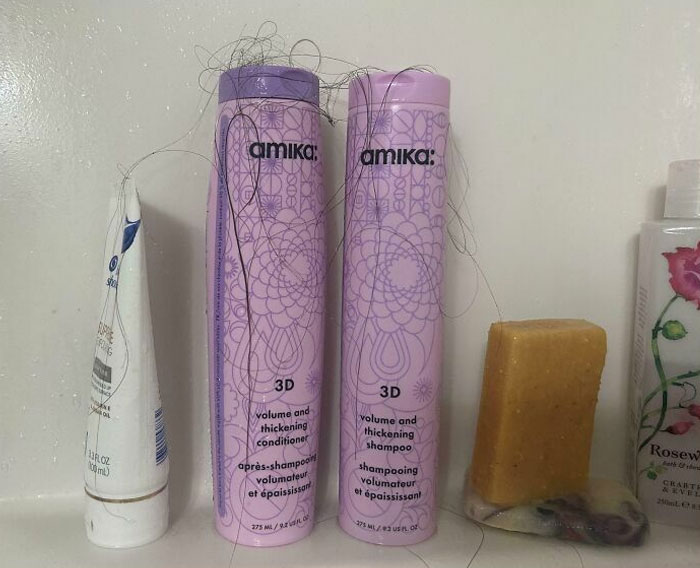 Amika shampoo and conditioner bottles covered in hair, illustrating a common issue with horrible roommates.