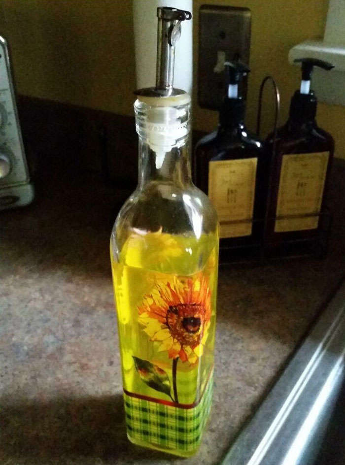 Oil bottle with sunflower design used as soap dispenser, showcasing horrible roommates' quirky habits.