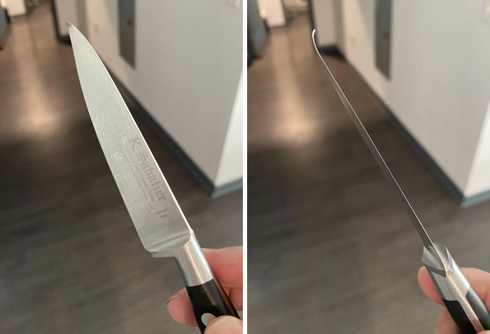 Dull kitchen knife with bent tip, possibly due to horrible roommates' misuse, held in hand over a wooden floor.