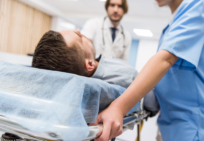 Person on a hospital stretcher with medical staff, related to insurance claims being denied.