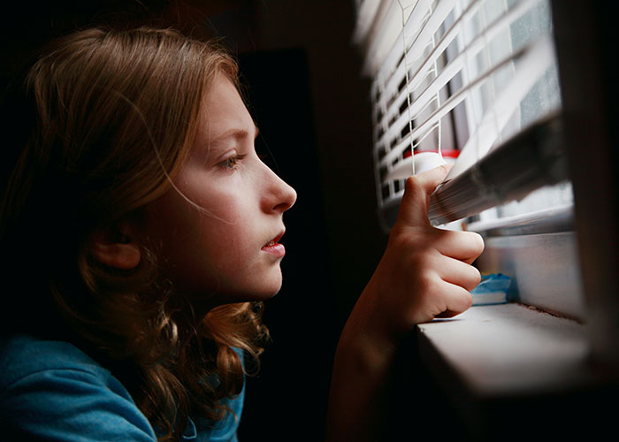 Child looking out window, pondering family issues.