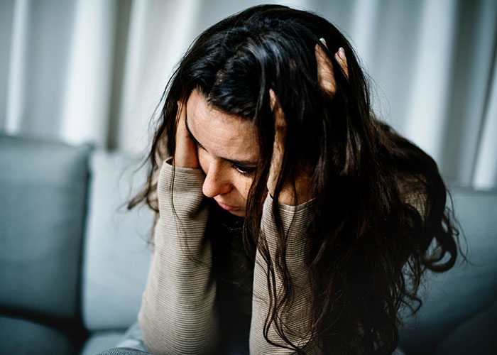 Woman feeling distressed, contemplating issues with stepdaughter's hostility affecting family dynamics.