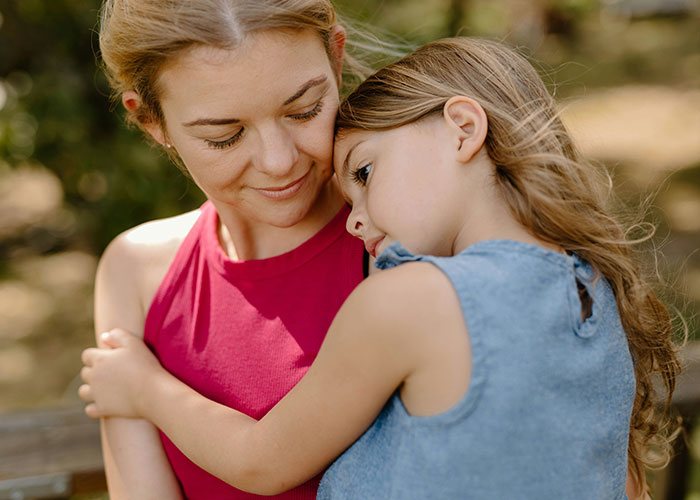 Mom contemplating marriage due to stepdaughter's emotions, comforting her in an outdoor setting.