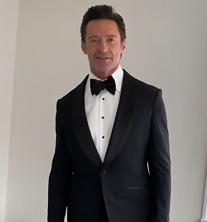 Man in tuxedo smiling indoors, sparking rumors on social media.