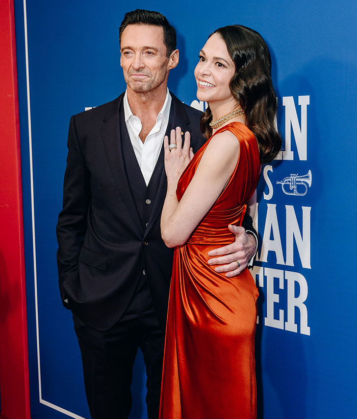 Man in suit with a mysterious woman in an elegant red dress at an event.