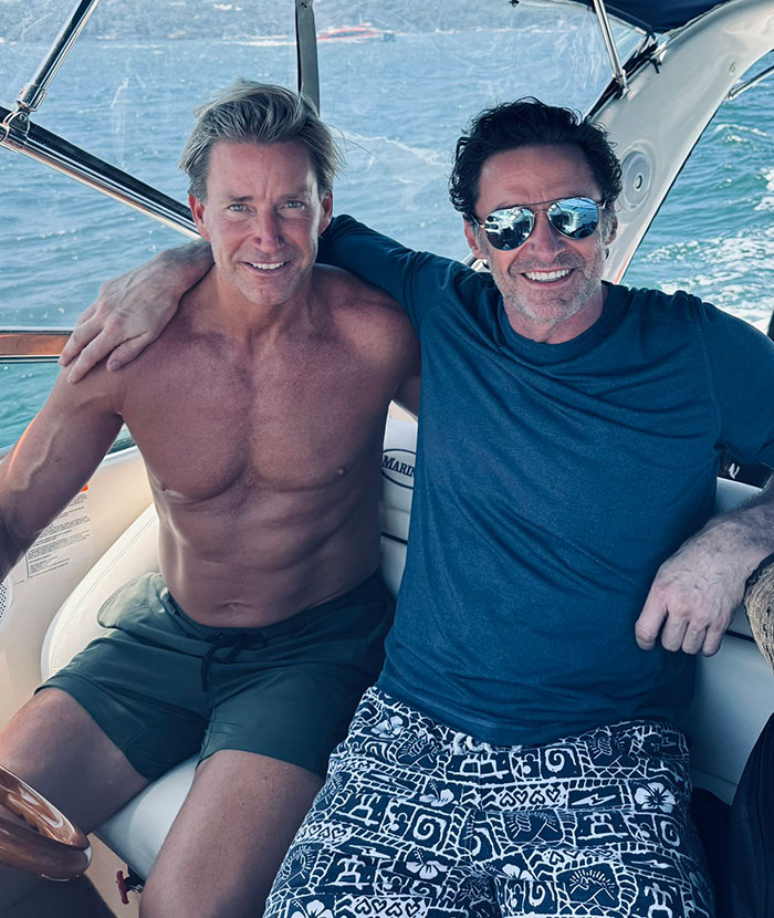 Two men on a boat smiling; rumors spark about Hugh Jackman with unknown figures.