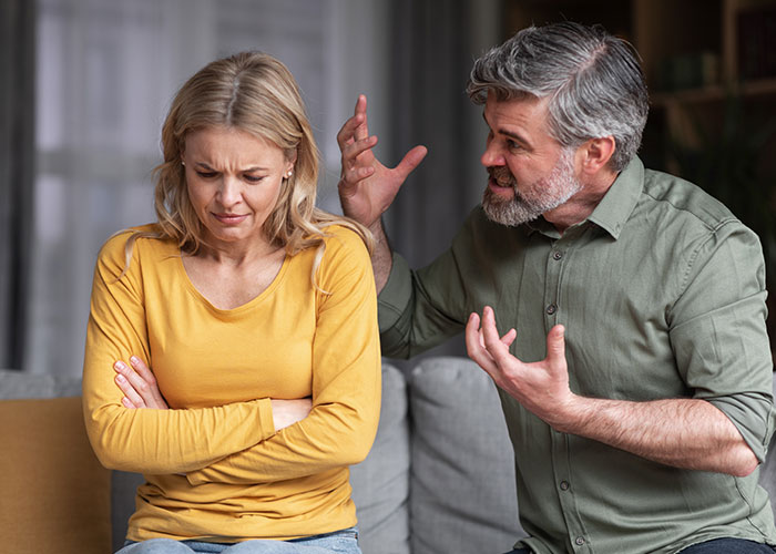 Man angry at wife while discussing Christmas budget on the couch.