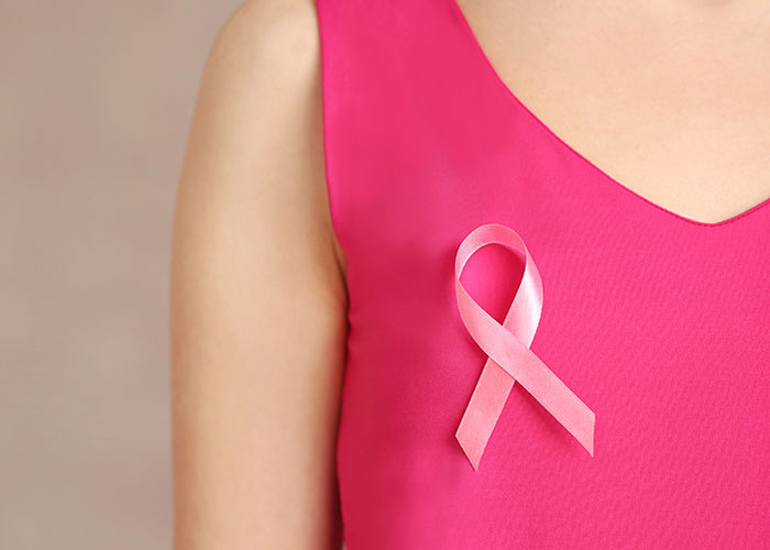 Person in a pink shirt wearing a breast cancer awareness ribbon.