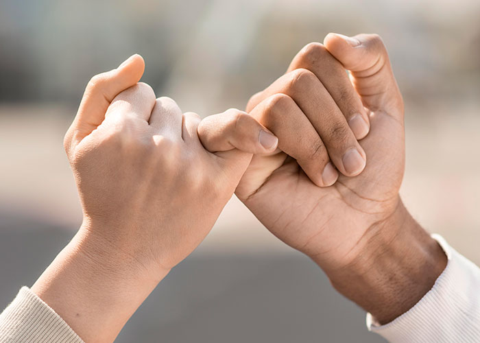 Two hands making a pinky promise, symbolizing support and understanding during a difficult time like surgery.