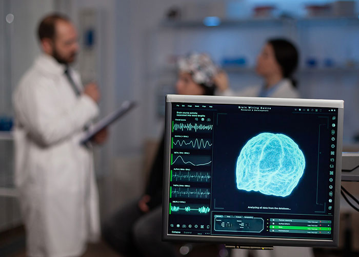 Brain surgery observation with doctors in discussion, displaying an MRI scan on the monitor.