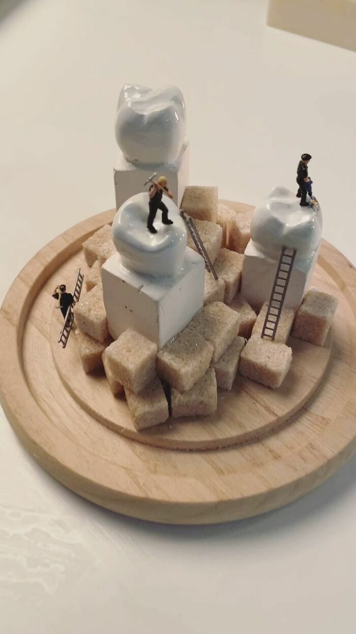 Miniature figures working on sugar cubes and teeth sculptures, showcasing the tiny world of foods and things.