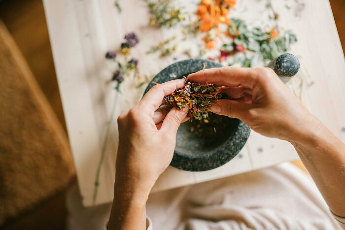 Hands using mortar and pestle, preparing herbs, symbolizing industries built on fooling people.