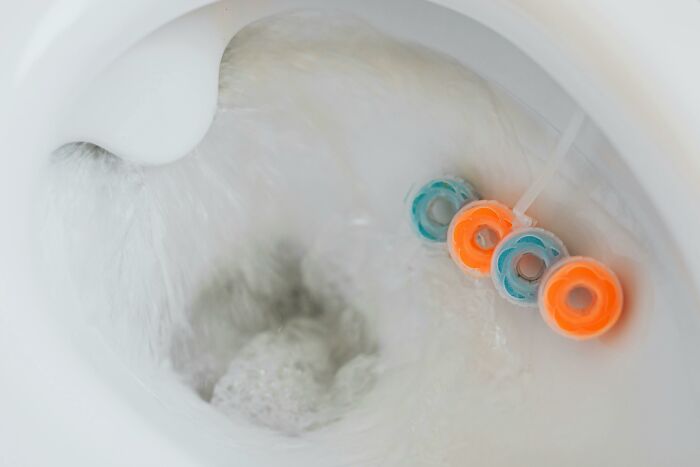 Toilet bowl with colorful cleaning rings attached, emphasizing industries built on fooling people.