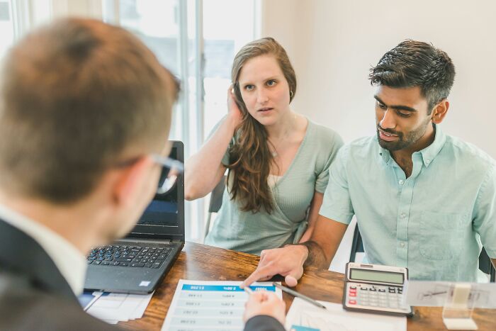 A couple discussing financial documents with a consultant, illustrating industries known for misleading practices.