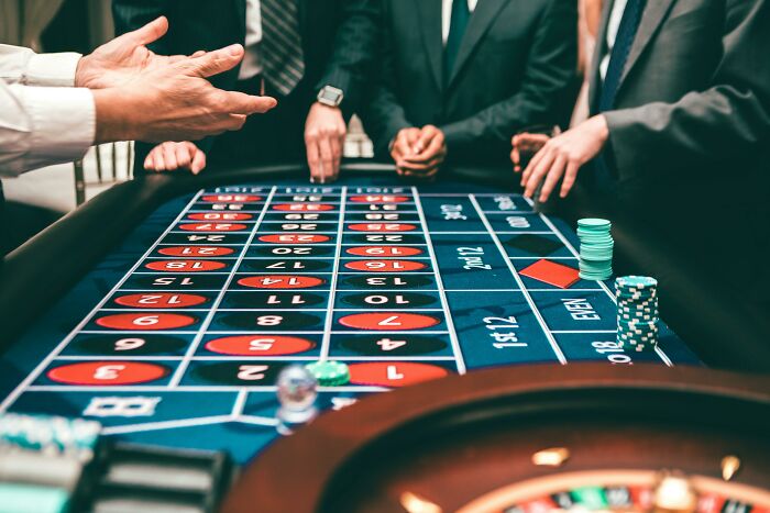 People around a roulette table in a casino, placing bets, linked to industries built on fooling people.