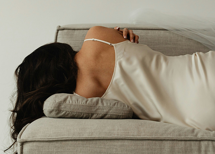 Woman in a satin dress lying on a sofa, evoking mixed emotions akin to insurance horror stories.