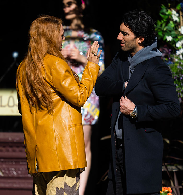 Man and woman talking outdoors, both in stylish jackets, for a scene involving discussions around Justin Baldoni.