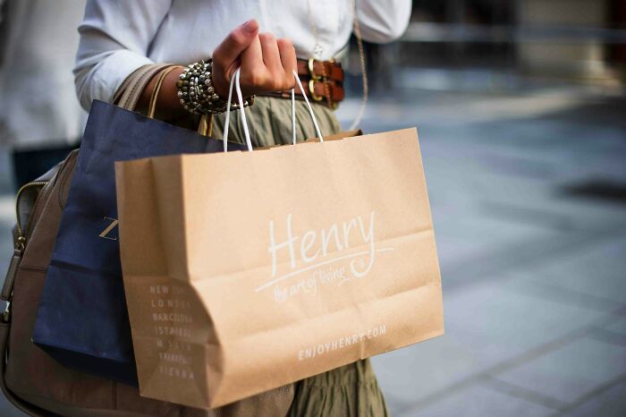 Rich kid carrying shopping bags, wearing stylish bracelets and a white top.