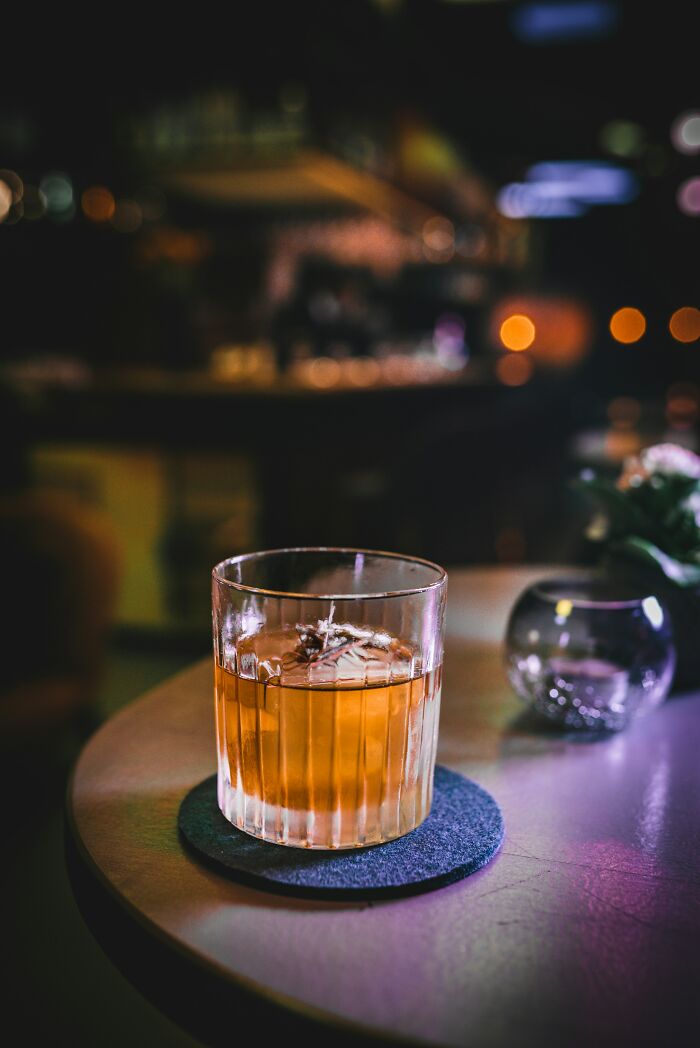 Orange cocktail on a table in a dimly lit bar, capturing a moment of reflection.