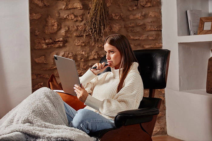 A woman looking upset while reading a tablet.