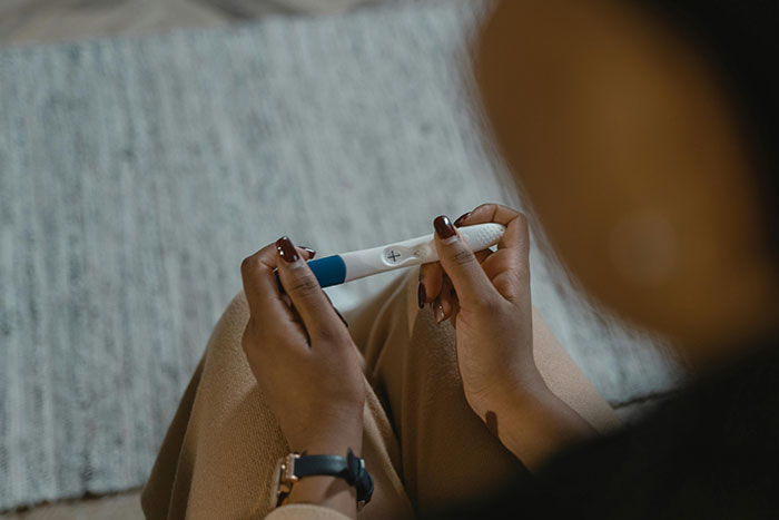 Person holding a pregnancy test, related to an accidental pregnancy.