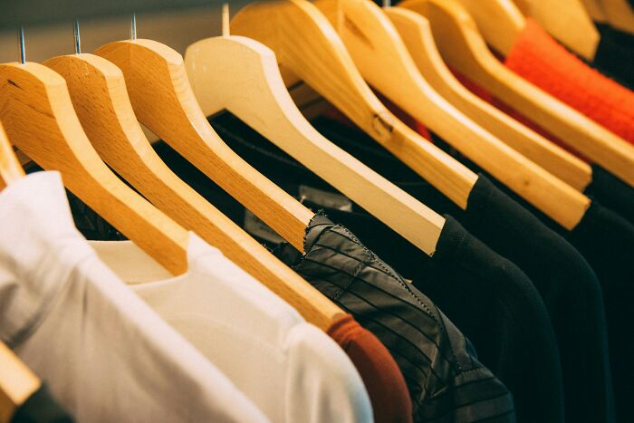 Clothes on hangers in a closet, illustrating frugal habits developed from being poor.