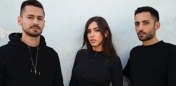 A group portrait featuring three individuals dressed in black, with a woman in the center associated with Kanye West's new wife.