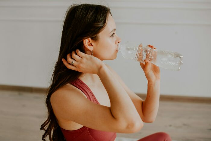 Woman in workout attire drinks water after exercise, highlighting doctors' advice on fitness.