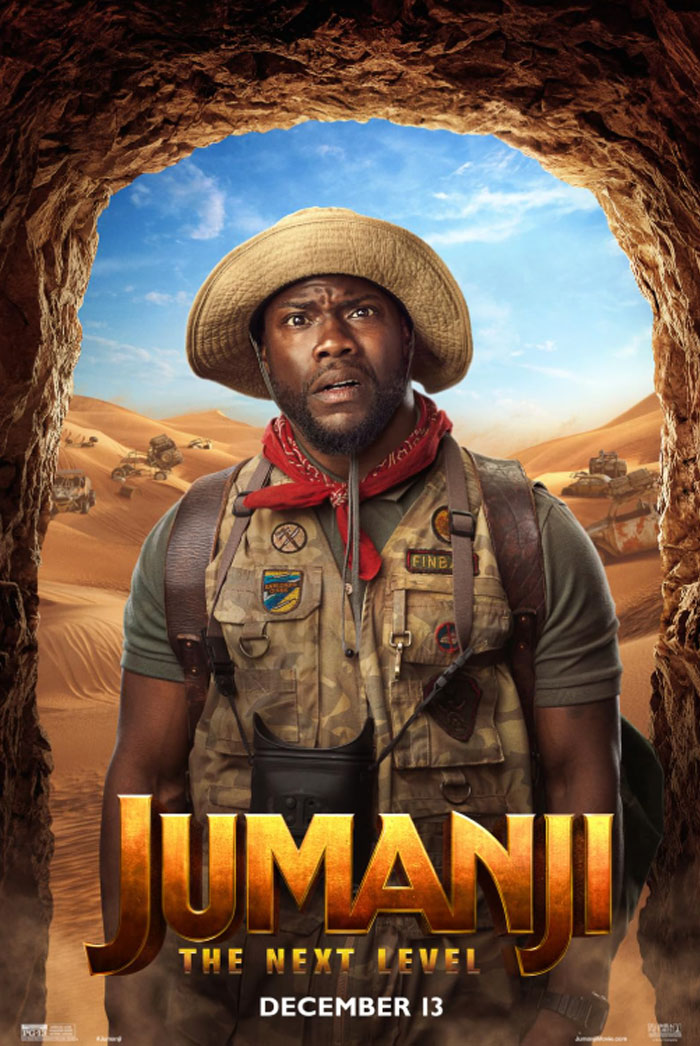 Kevin Hart dressed as his character from "Jumanji: The Next Level," wearing safari gear and a surprised expression, with desert scenery.