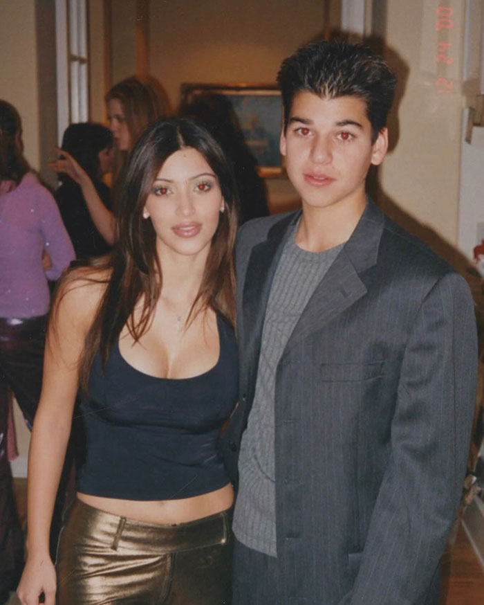 Young Kim Kardashian and her brother Rob Kardashian posing together indoors, sparking fan debate over her appearance and plastic surgery rumors.