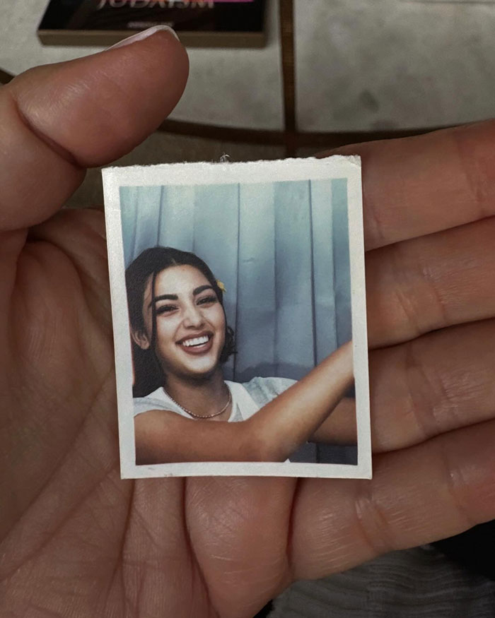 Kim Kardashian holding photo of her young self in hand, sparking discussion on her natural looks and plastic surgery.