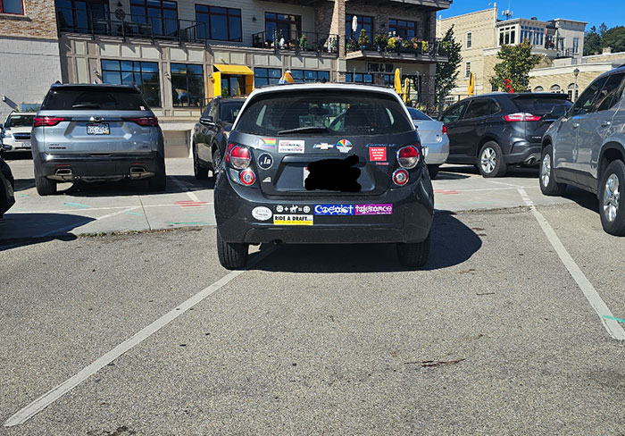 Car parked poorly across two spaces, showing lazy-infuriating behavior in a busy parking lot.