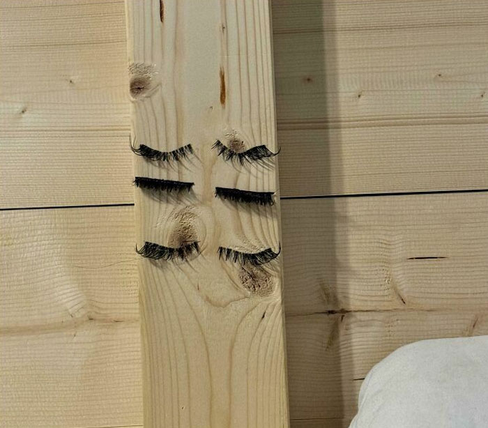 Wood plank with fake eyelashes, resembling a face, symbolizing lazy-infuriating-people theme.