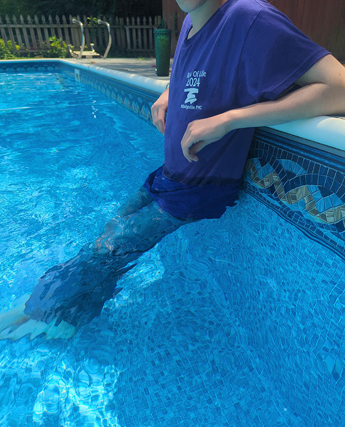 Person lounging on a pool's edge in a t-shirt and shorts, exemplifying lazy-infuriating-people behavior.