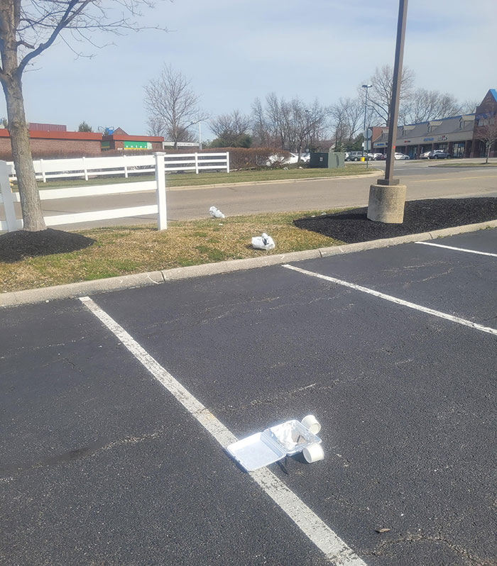 Discarded trash in an empty parking lot, illustrating lazy, infuriating behavior.