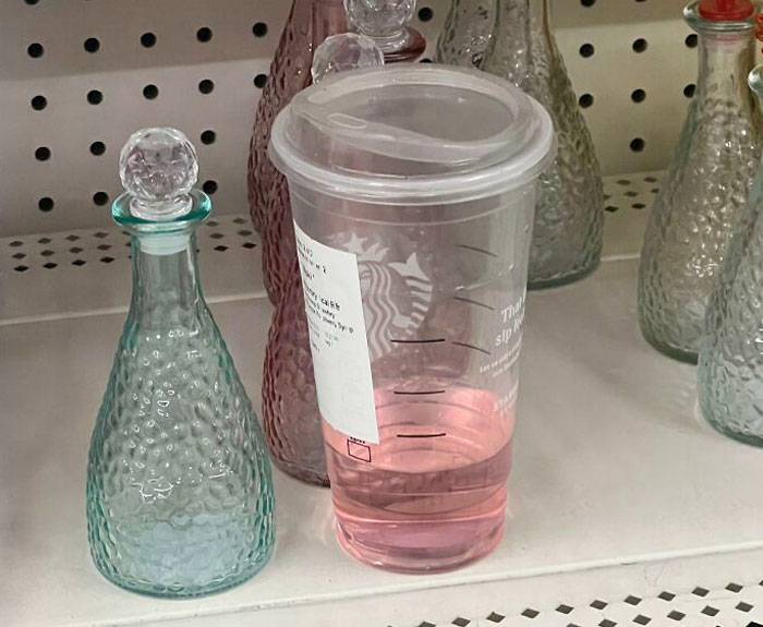 Starbucks cup misplaced among glass bottles, highlighting lazy-infuriating behavior.