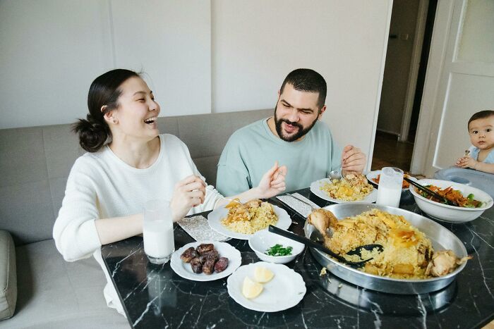 Left-handed person at a dining table with family, using spoon with left hand, enjoying a meal together.